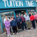 Smiles all round as Ready2Work Academy students stand outside Tuition Time with teachers and facilitators, celebrating the success of their showcase café event.