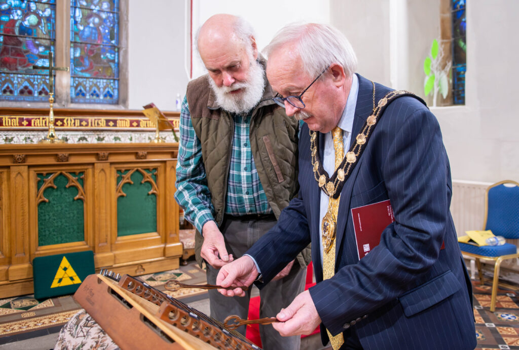 Dick Glasgow teaches the Mayor Gordon how to play the dulcimer.
